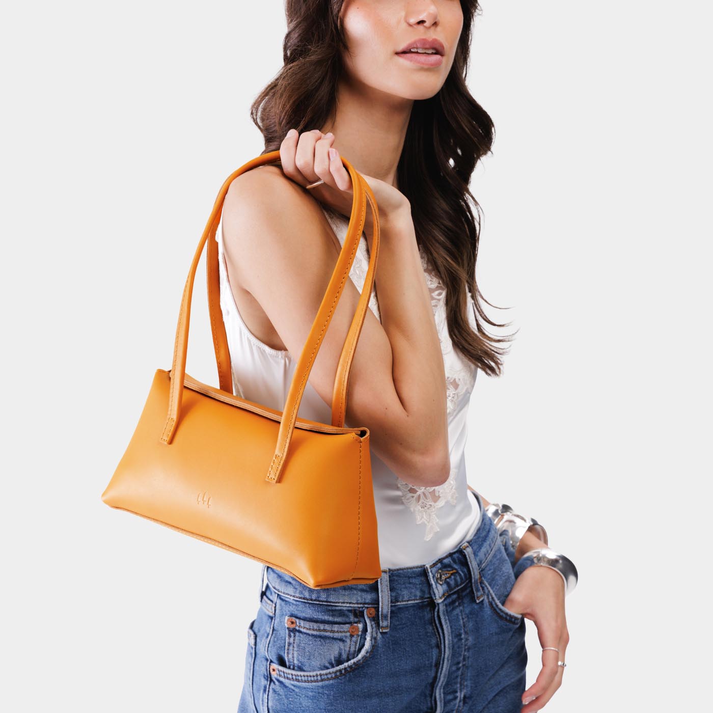 Sunflower | Woman wearing a dark yellow leather bowler bag against a white background