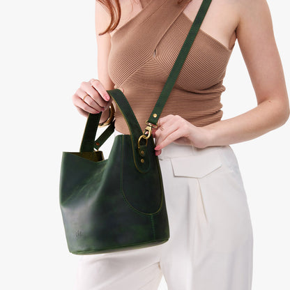 Evergreen*Large | Model holding symmetrical bucket bag with handle, latch closure, and removable crossbody strap