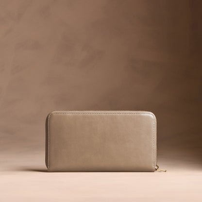 Satine | Full zip around wallet with a strap on a brown background