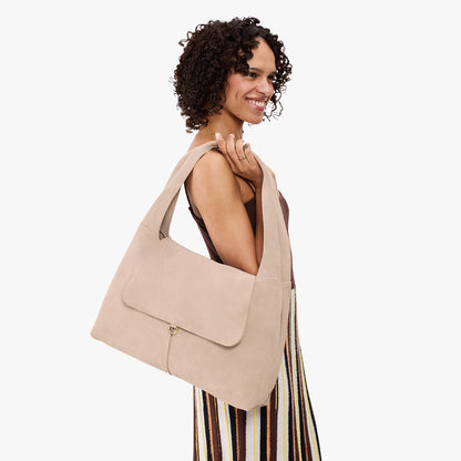 Taupe*Large | A model holding a slouchy triangle shaped shoulder bag with a flap