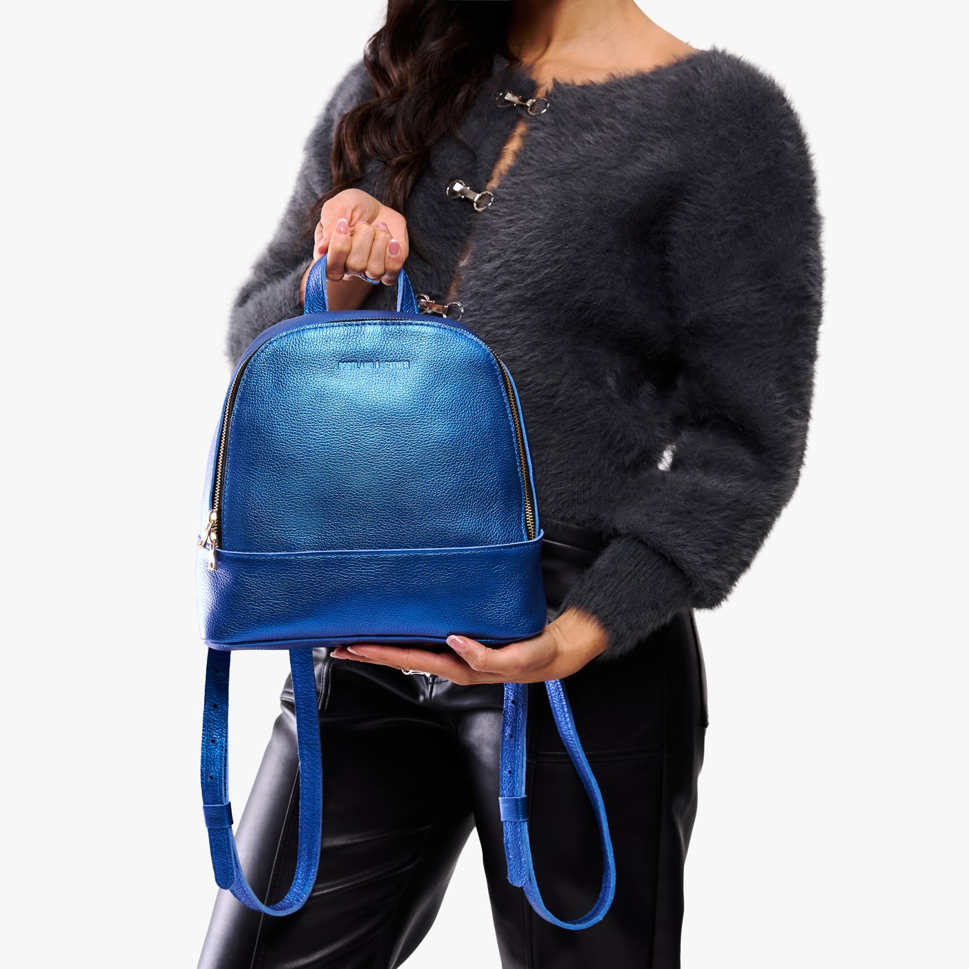 Comet Blue | Model holding leather backpack with debossed Portland Leather logo on front