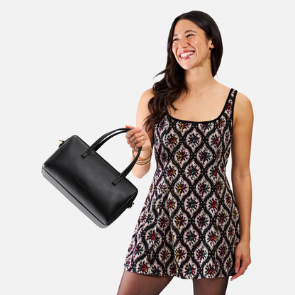 Black*Oversized | Model holding mini duffle shaped handbag with crossbody strap