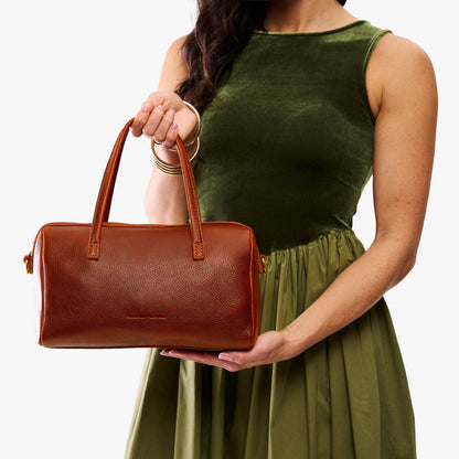 Nutmeg*Oversized | Model holding mini duffle shaped handbag with crossbody strap