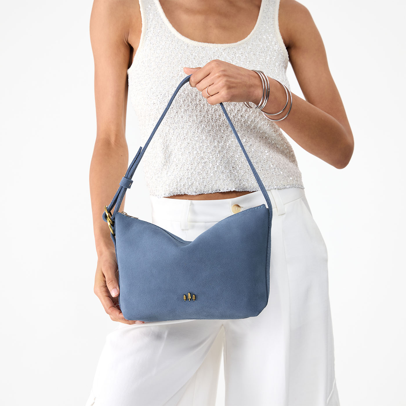 Denim*Small | Model holding a Slouchy Shoulder Bag that has a zipper opening and three metal tree emblems