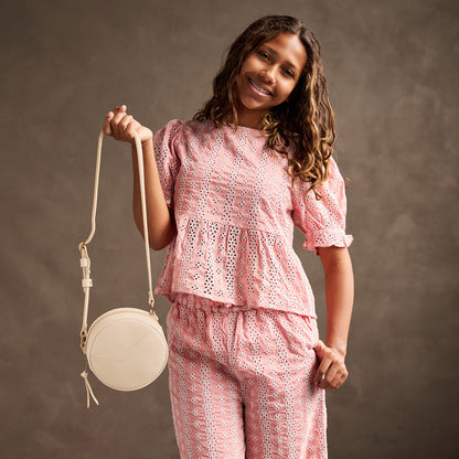 Pebbled Bone | Model holding a circle shaped crossbody bag with top zipper and gold accents