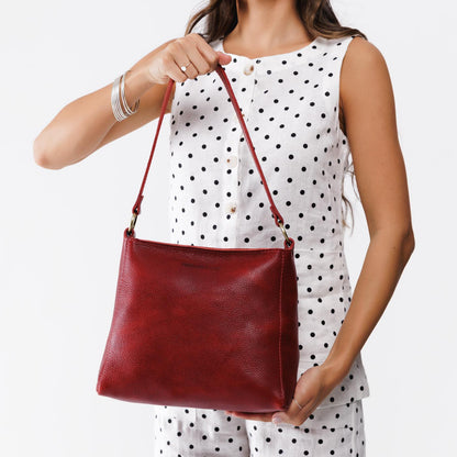 Chili Red*Small | Model holding triangular shoulder bag with antiqued brass finished hardware